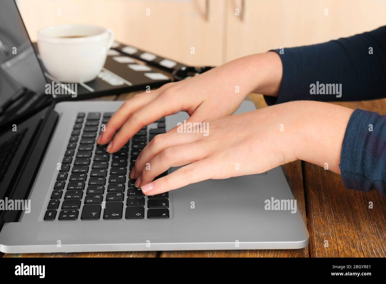 Female hands of scriptwriter working on laptop at desk on cupboard ...