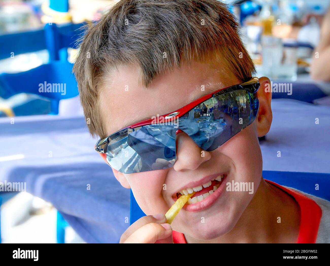 caucasian little boy with sunglasses eating unhealthy potatoes Stock Photo