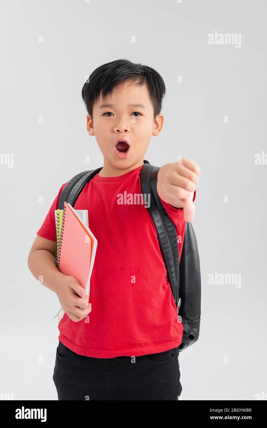 Beautiful student kid boy wearing backpack holding books over isolated white background with angry face, negative sign showing dislike with thumbs dow Stock Photo