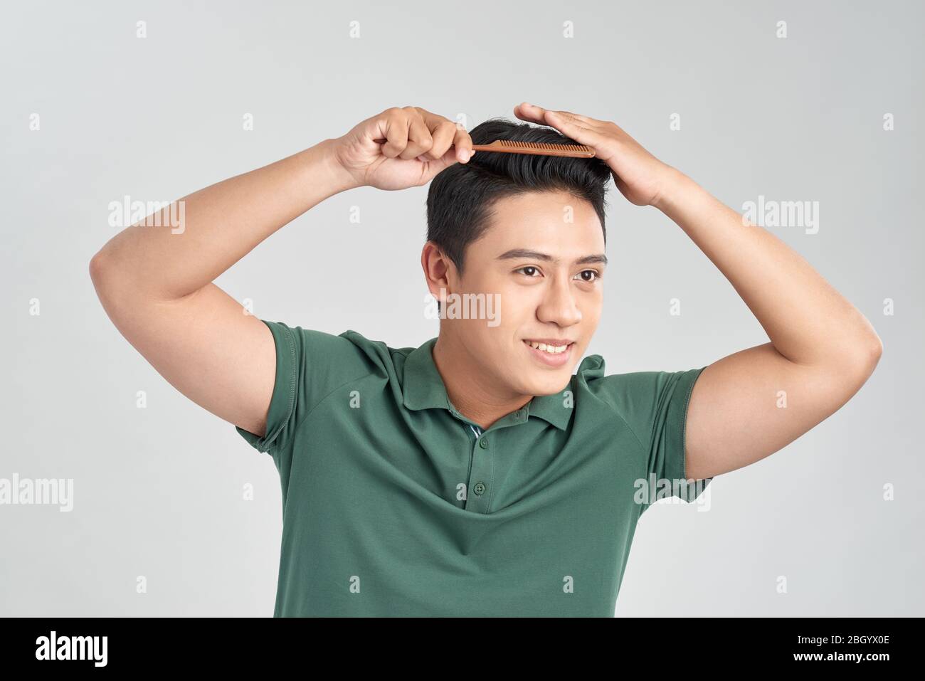 Closeup photo of macho cheerful mature guy holding hairbrush making hair styling isolated white background Stock Photo