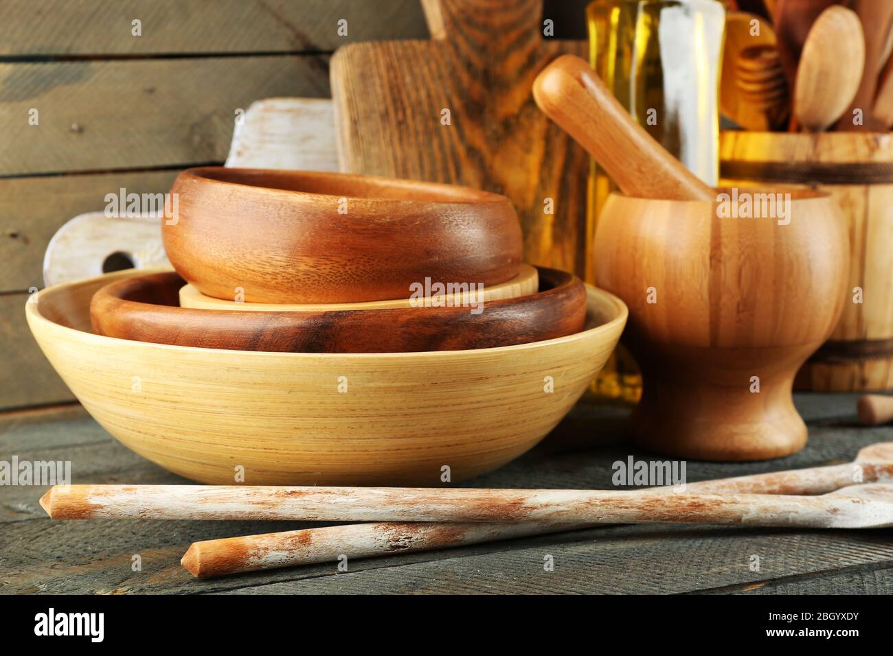 Wooden kitchen utensils with glass bottle of olive oil on wooden planks
