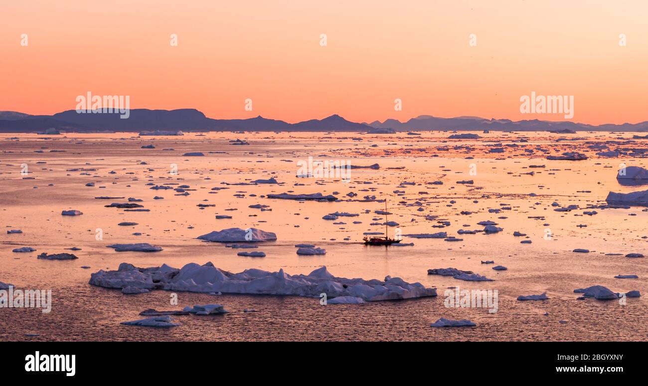 Global Warming and Climate Change - Icebergs and ice from melting glacier in icefjord in Ilulissat, Greenland. Aerial photo of arctic nature ice landscape. Unesco World Heritage Site. Boat for scale. Stock Photo