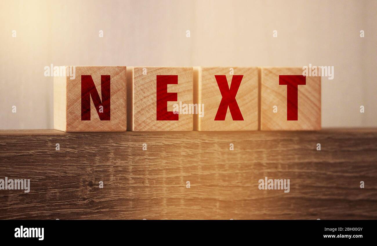 The word Next on wooden blocks on wooden table. Next steps plan ...