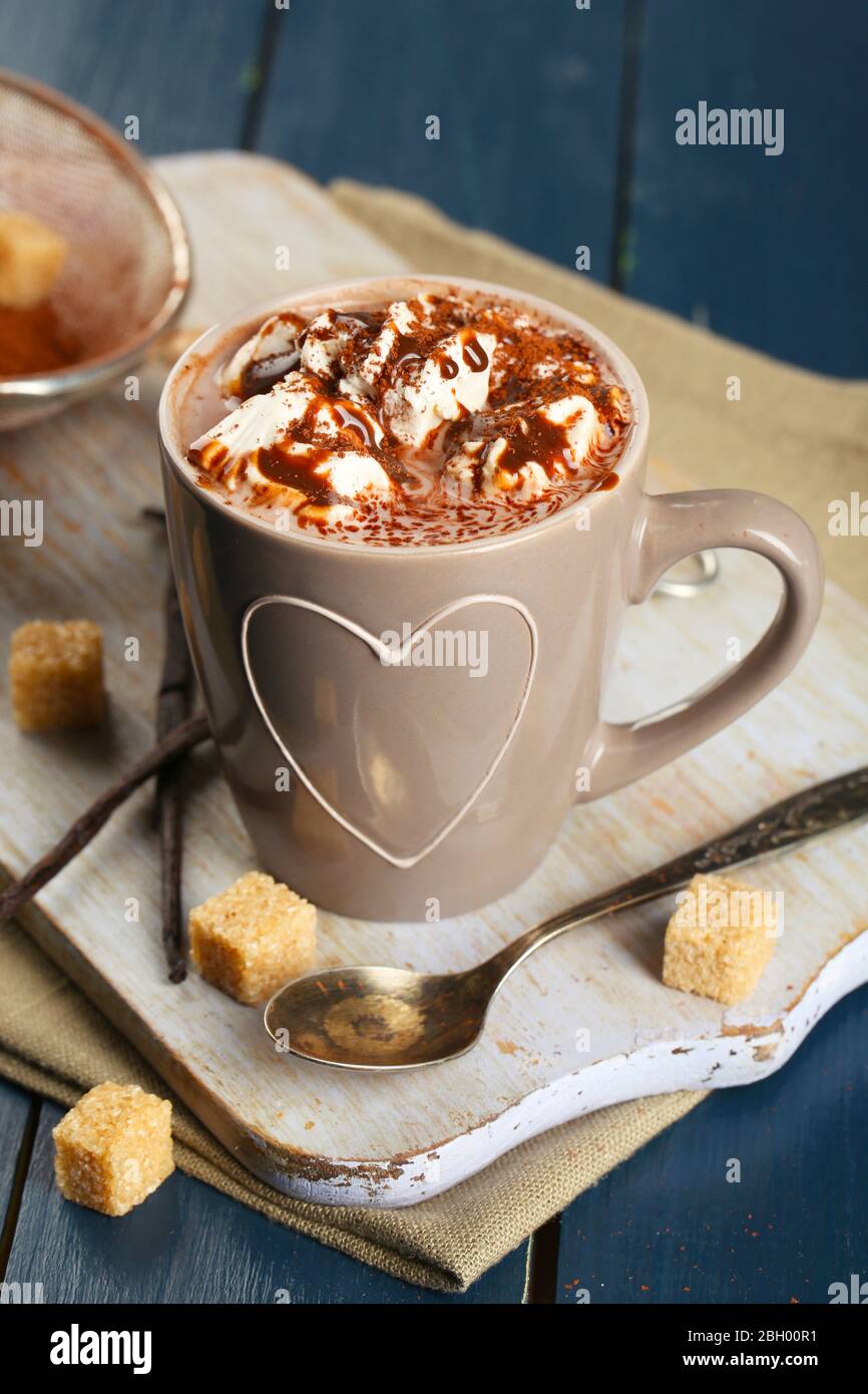 Cup of hot coffee with marshmallow on cutting board with sieve of cocoa ...