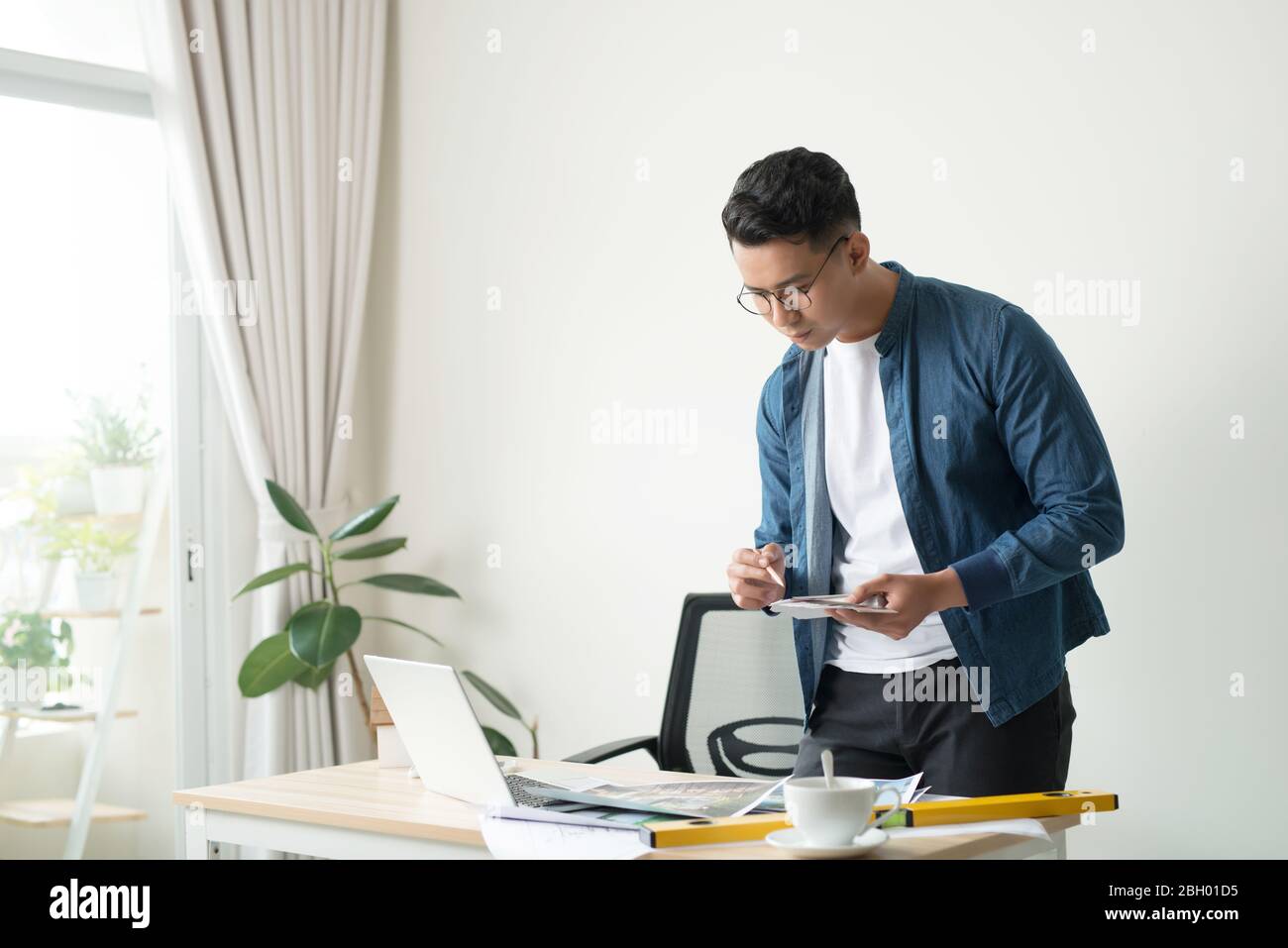 Profile shot of a young male architect working on blueprints at his desk at the office copyspace building plans construction project engineer expert s Stock Photo