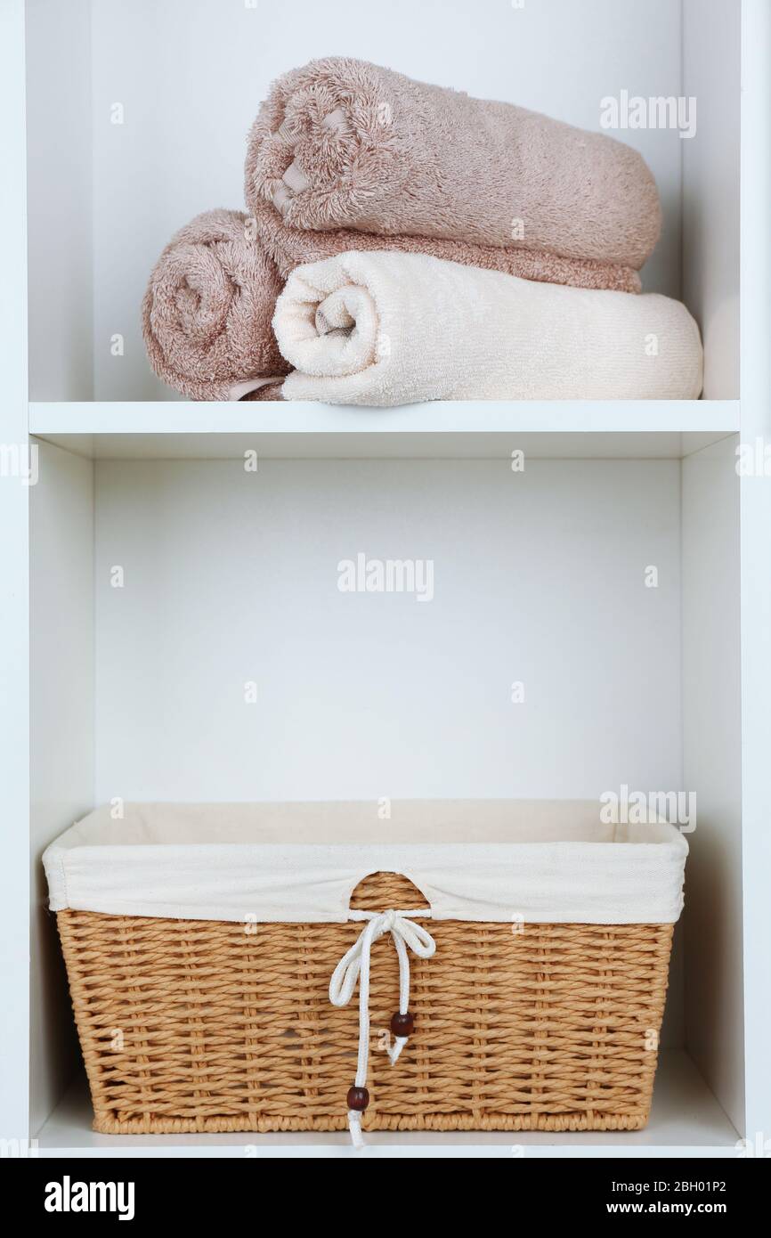 Rolled towels with wicker basket on shelf of rack background Stock Photo Alamy