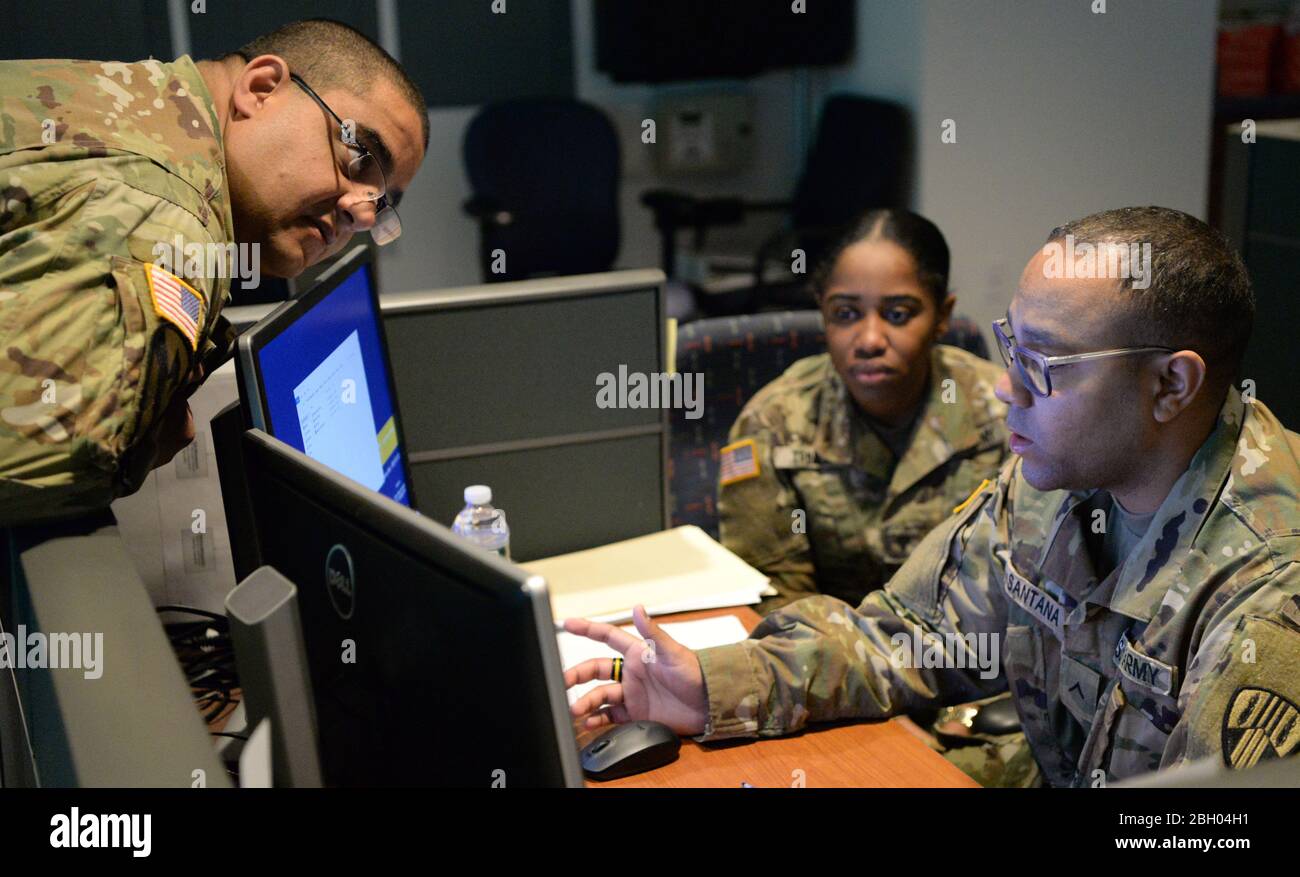 Members of the New York Army National Guard discuss procedures at the Coronavirus Hotline, call center in Hawthorne, N.Y., March 16, 2020. The New York State Department of Health established a toll-free Coronavirus Hotline (1-888-364-3065). (U.S. Air National Guard photo by Senior Airman Sean Madden) Stock Photo