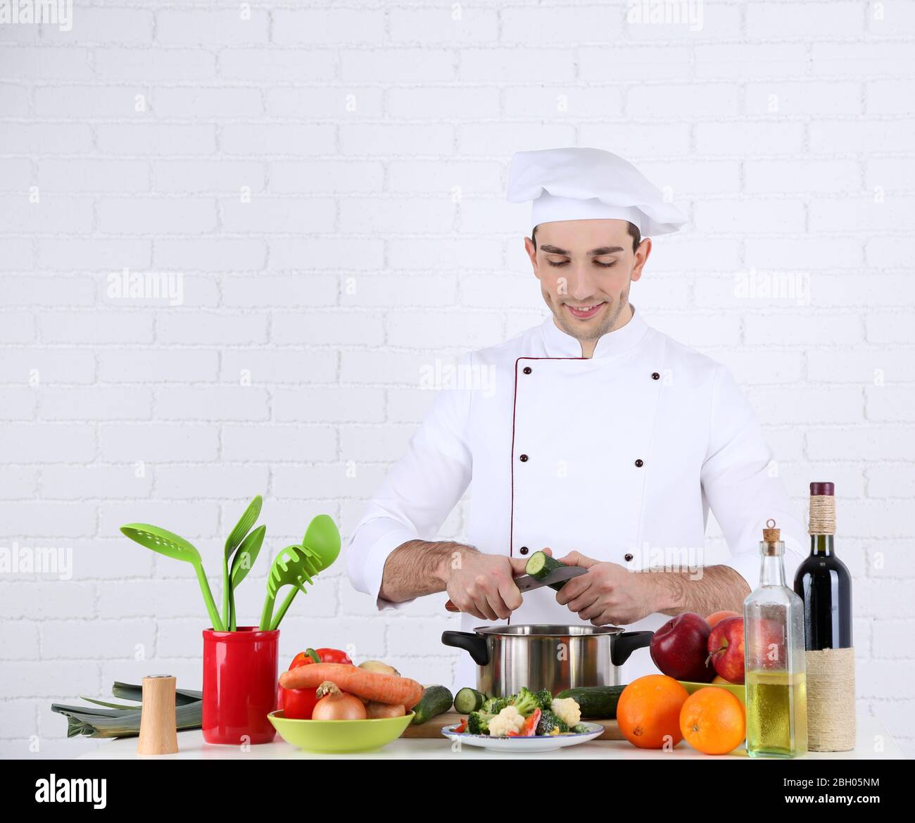 Chef at table with different products and utensil in kitchen on white ...