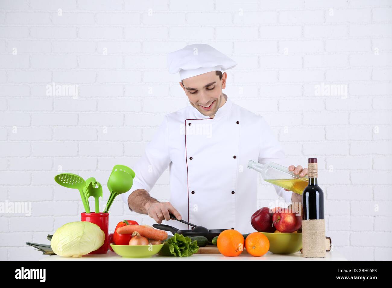 Chef at table with different products and utensil in kitchen on white ...