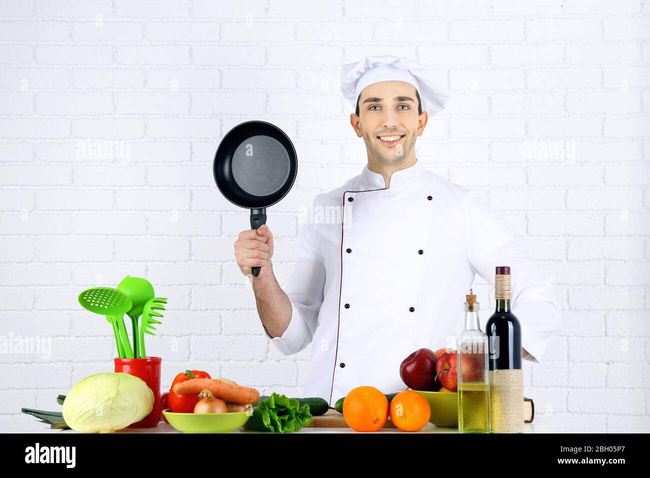 Chef at table with different products and utensil in kitchen on white ...