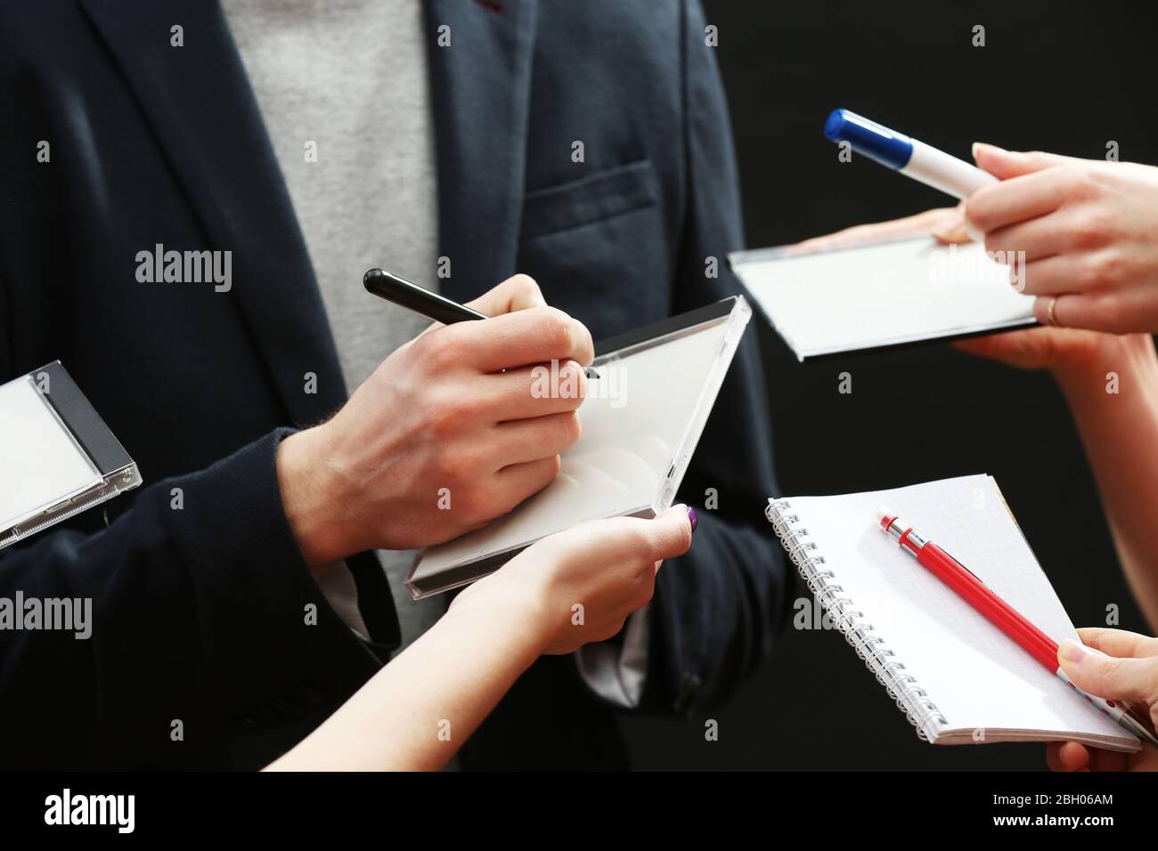 Elegant man signing autograph in notebook on dark background Stock Photo