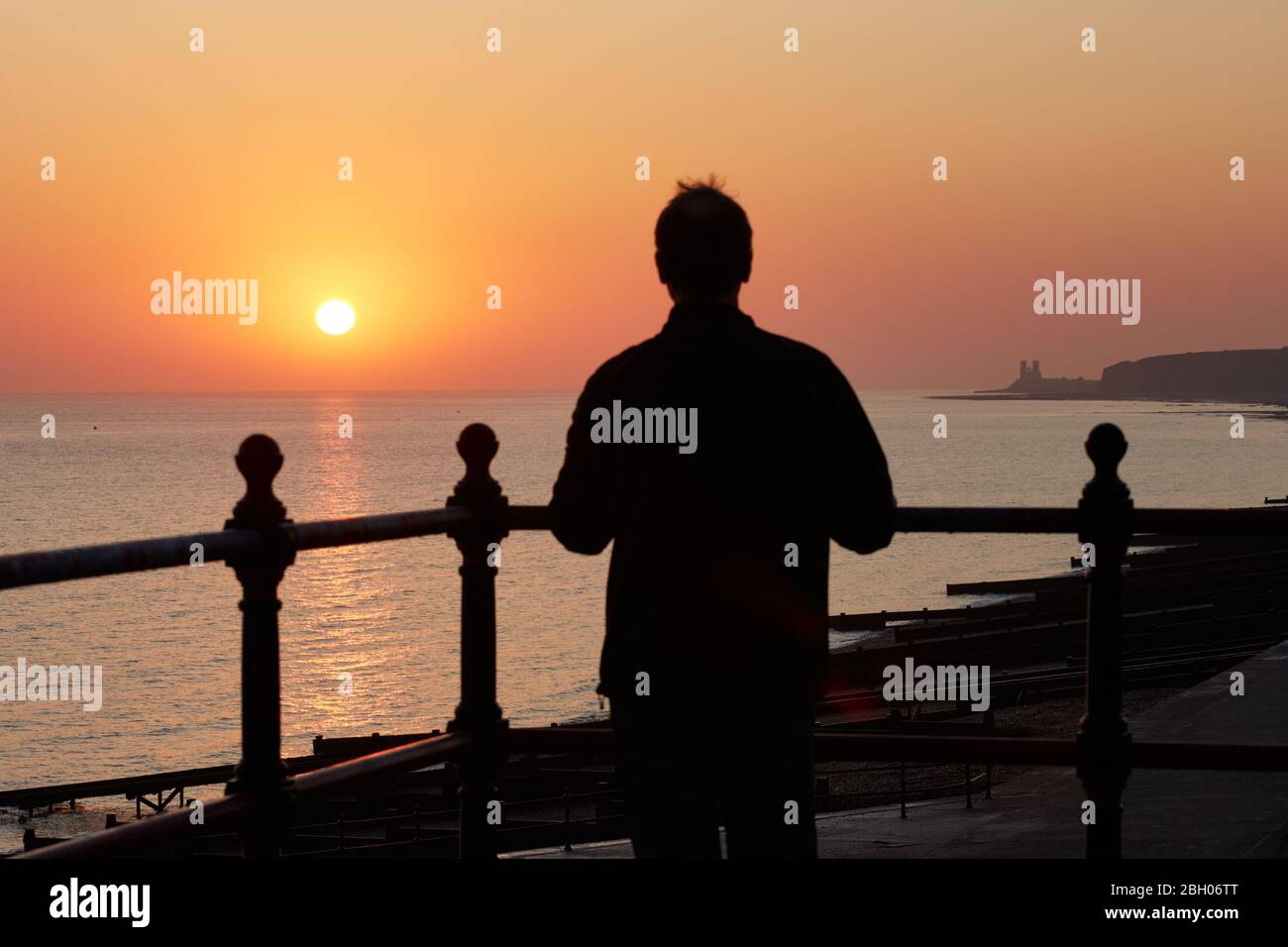 Herne Bay, Kent, UK. 23rd April 2020: UK Weather. A man watches the sunrise at Herne Bay in Kent on St Georges day and the 245th anniversary of the birthday of the painter JMW Turner thought to have been born on this day 1775. Turner painted many pictures on the North Kent coast and the scene with Reculver Towers on the right would have been a familiar sight which did feature in at least one painting. Credit: Alan Payton/Alamy Live News Stock Photo