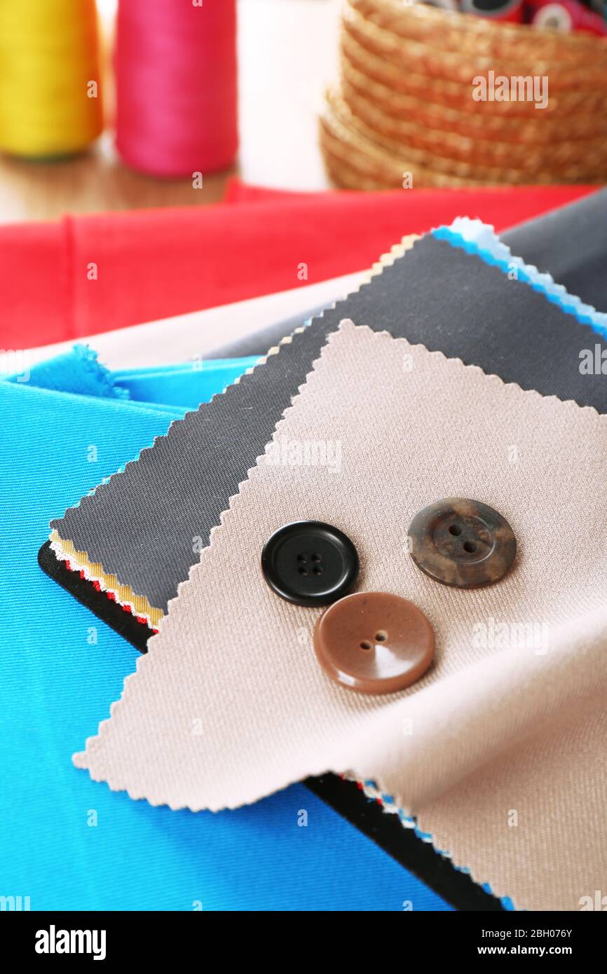 Colorful fabric samples with buttons and threads on wooden table background Stock Photo