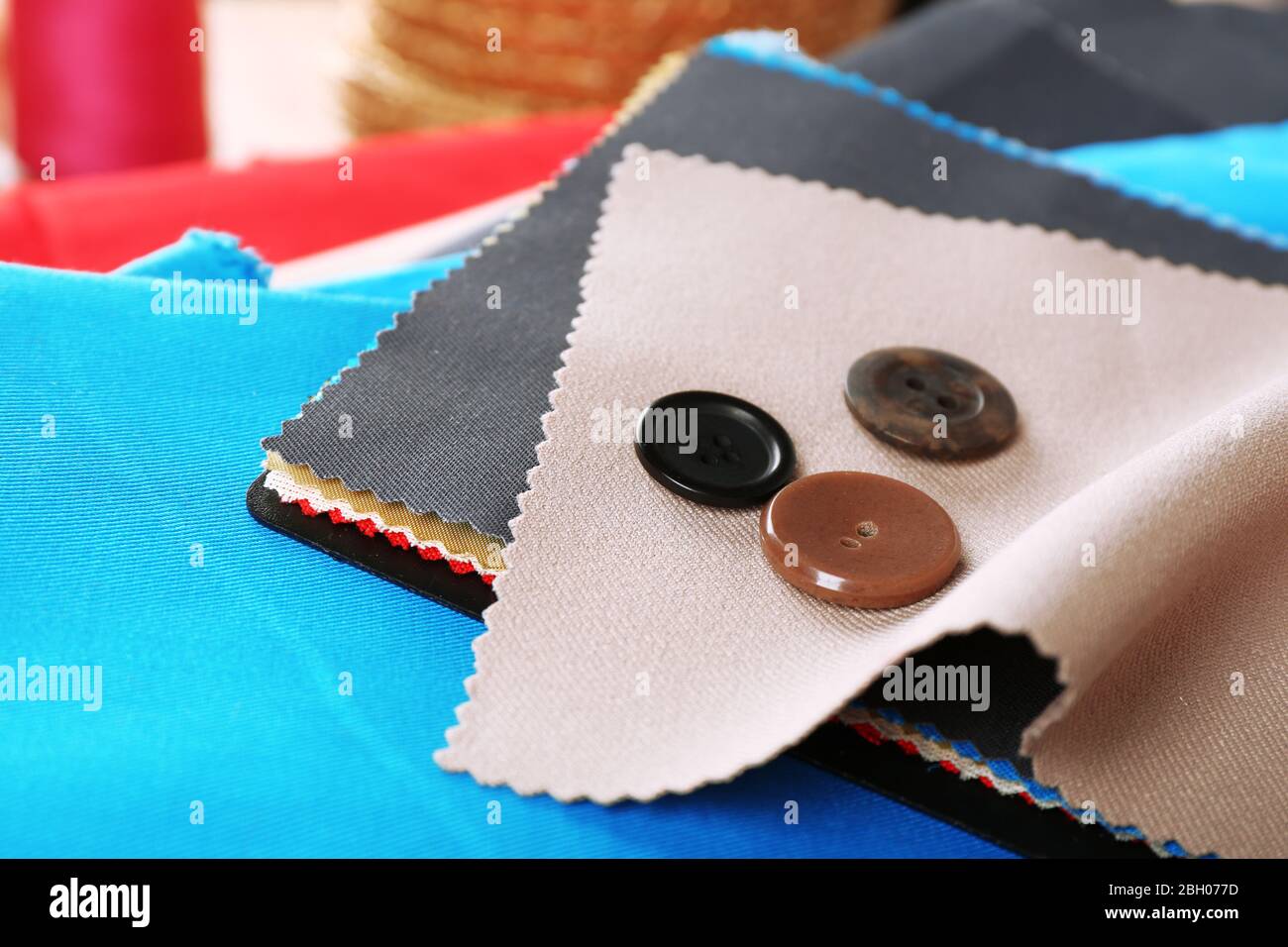 Colorful fabric samples with buttons and threads on wooden table background Stock Photo