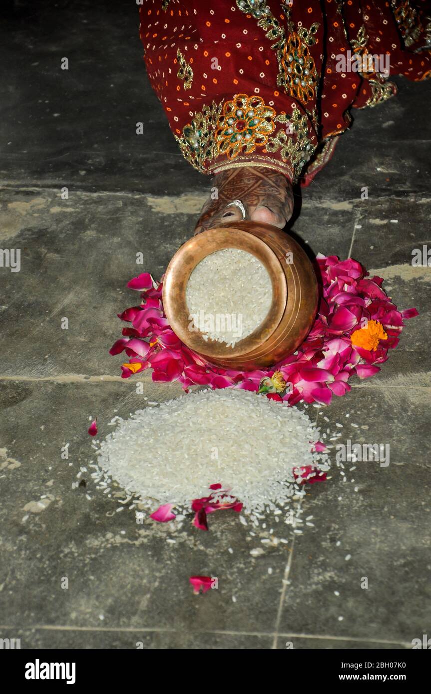 Indian bride pushing pot filled with rice in wedding, Indian marriage traditions Stock Photo