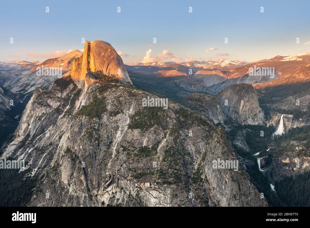 The Half Dome peak and Yosemite Falls waterfall as seen from Glacier Point at sunset Stock Photo