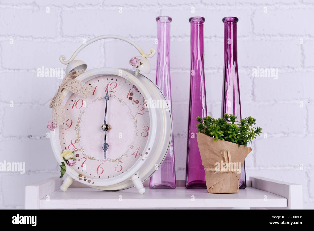 Interior design with alarm clock, plant and decorative vases on ...