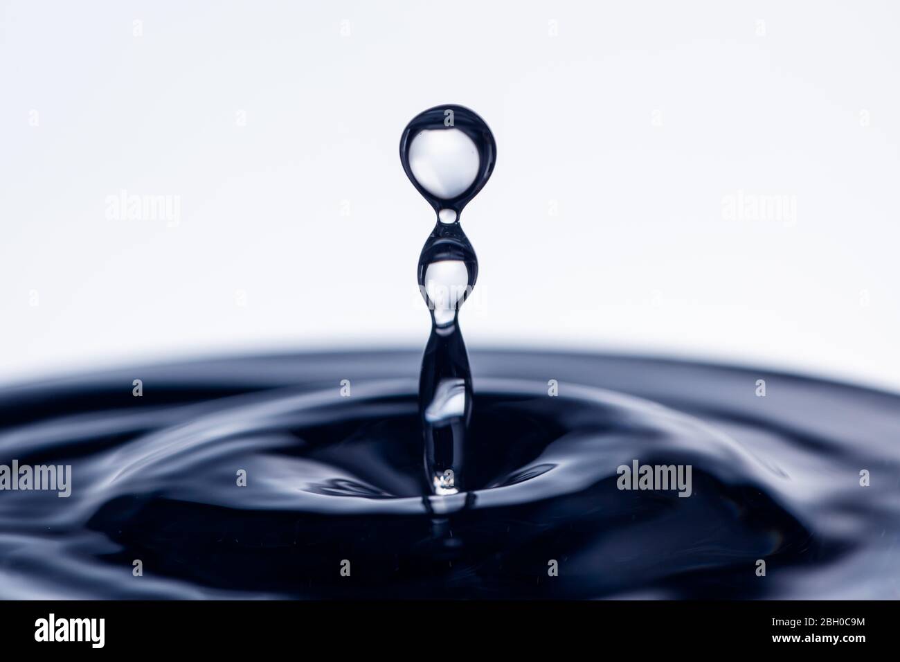 Closeup Of A Single Water Droplet Hitting The Surface Dark Blue White Background Stock Photo Alamy