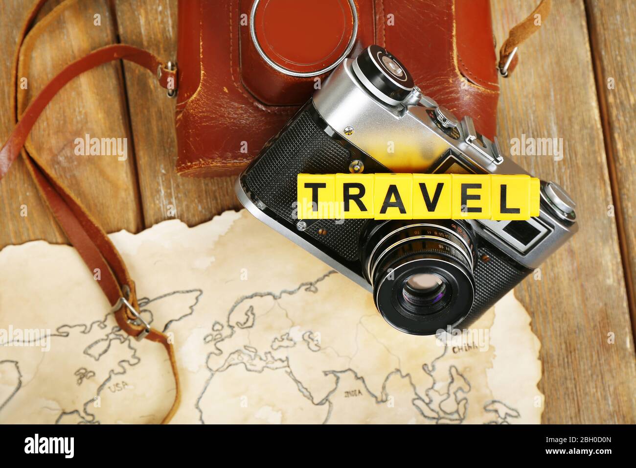 Retro camera on world map with word Travel on wooden table background Stock Photo