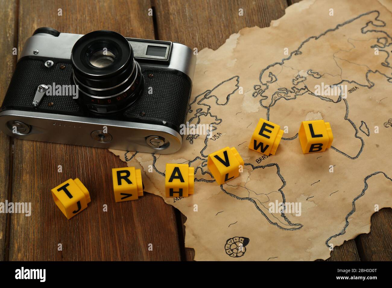 Retro camera on world map with word Travel on wooden table background Stock Photo