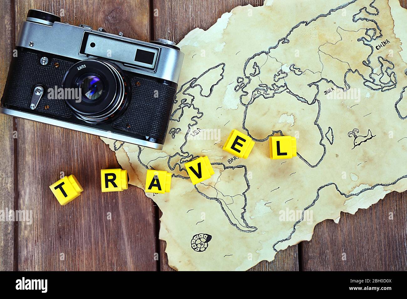 Retro camera on world map with word Travel on wooden table background Stock Photo