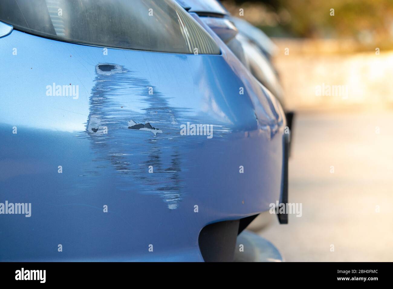 Scratch on a bumper of a blue car on a public parking. Not a rare scene