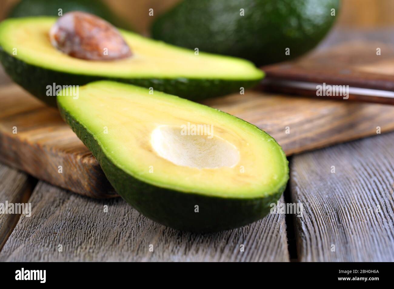 Avocado with knife on cutting board on wooden background Stock Photo ...