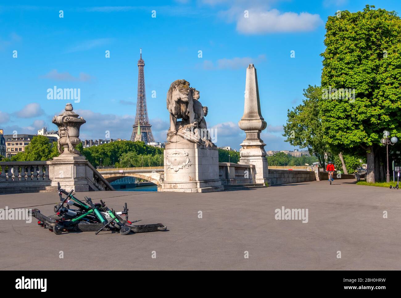 France. Summer sunny day in Paris. Seine embankment overlooking the Eiffel Tower. Heap of rental electric scooters on the pavement Stock Photo