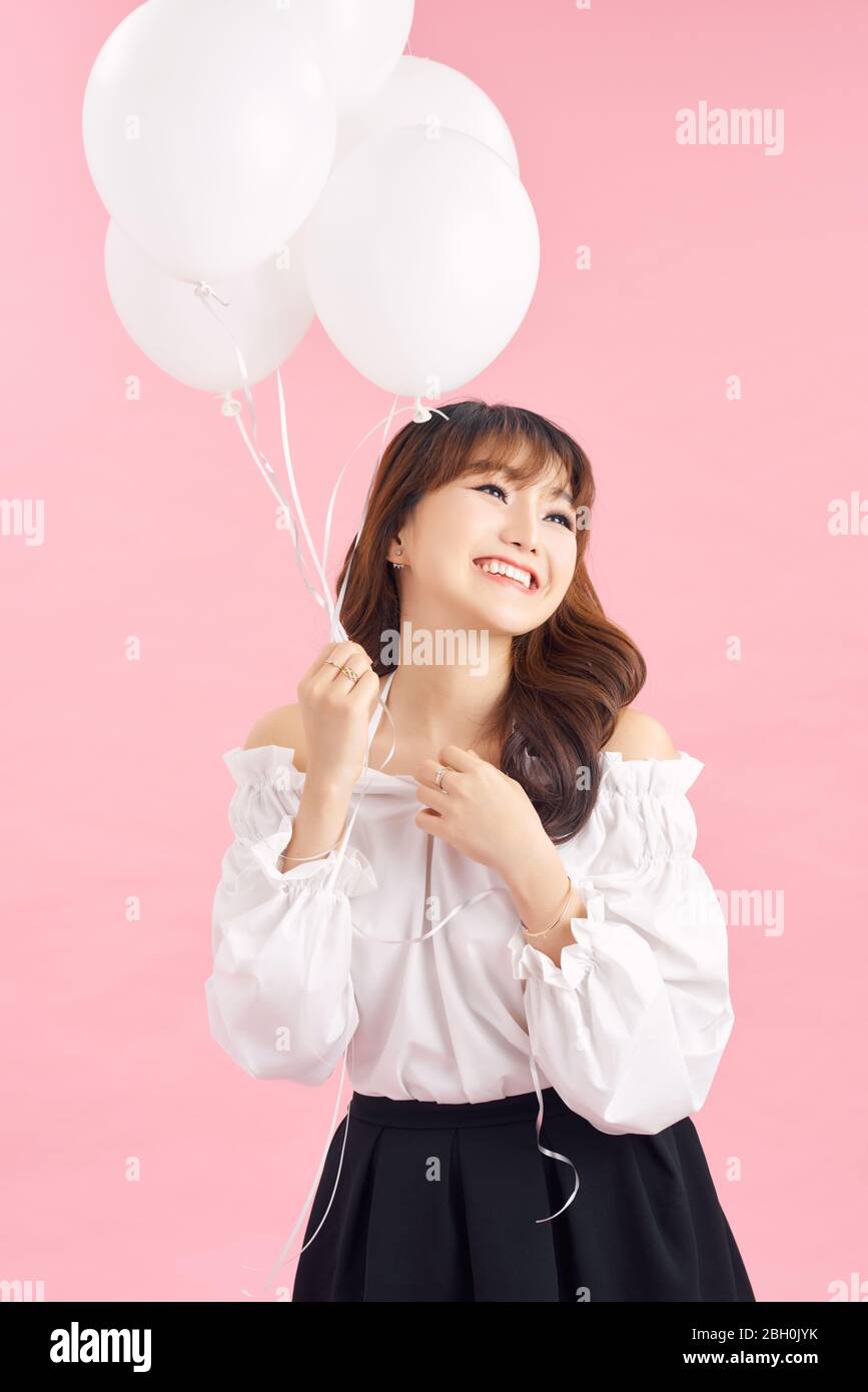 Portrait of smiling happy lady with air balloons on pink background. People concept Stock Photo