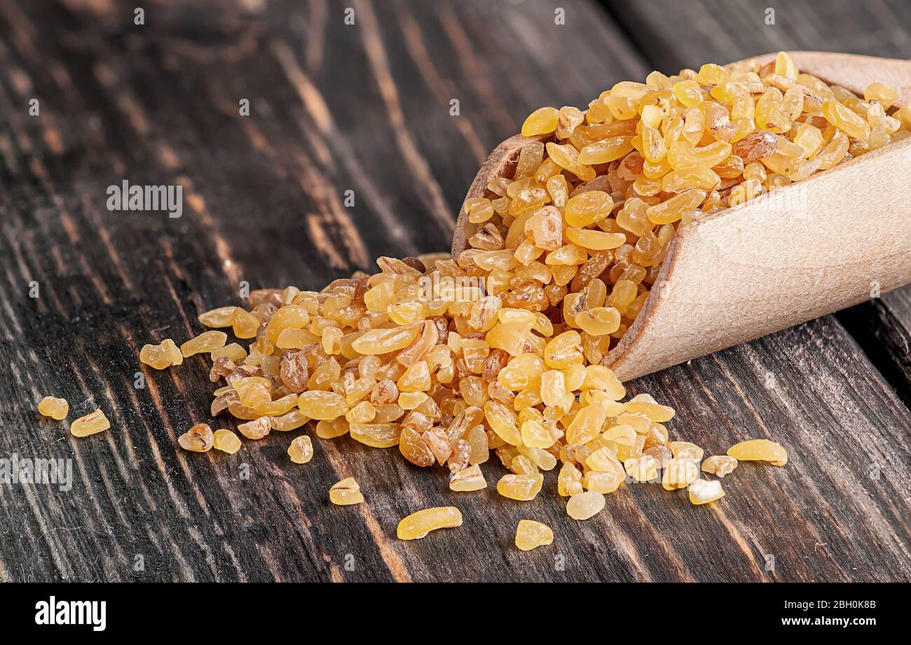 Bulgur in wooden scoop closeup Stock Photo