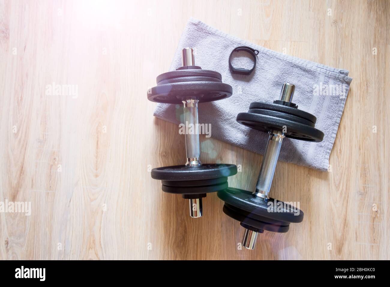 Two dumbbells and a fitness bracelet with a clock on the floor with a towel, home workout Stock Photo