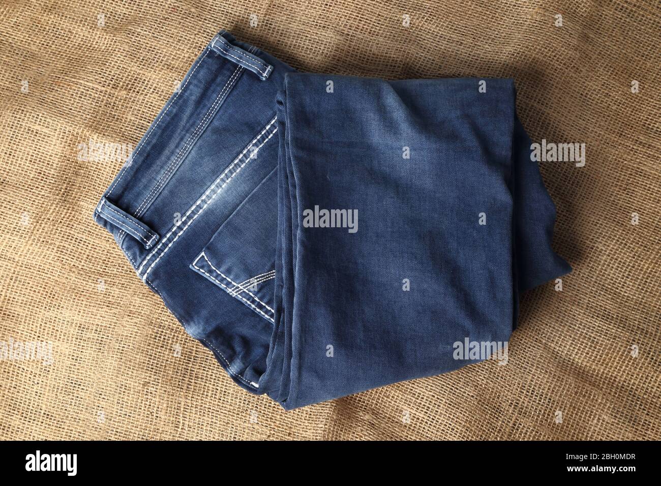 Old Blue jeans fashion design On brown hemp sack texture background,.Ripped jeans of a stack Hipster fashion copy space for text commentary . Stock Photo
