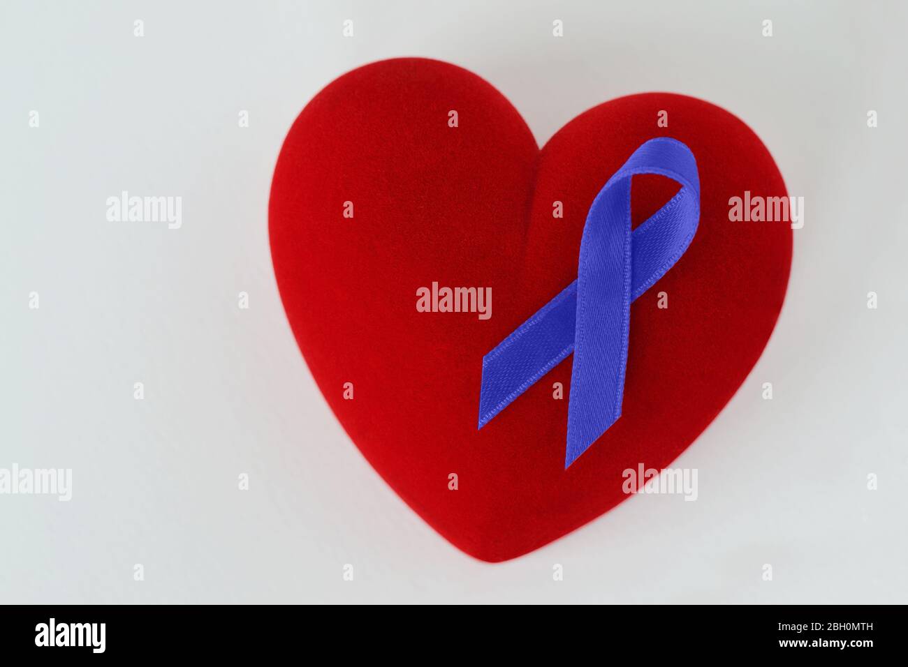 Heart with blue ribbon on white background - Concept of prostate cancer awareness Stock Photo