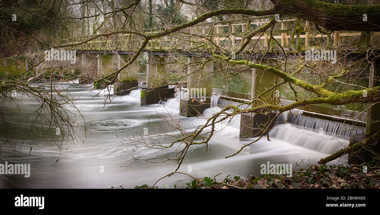 Long exposure silky smooth water flowing over man made structures at Beeleigh waterfalls Stock Photo