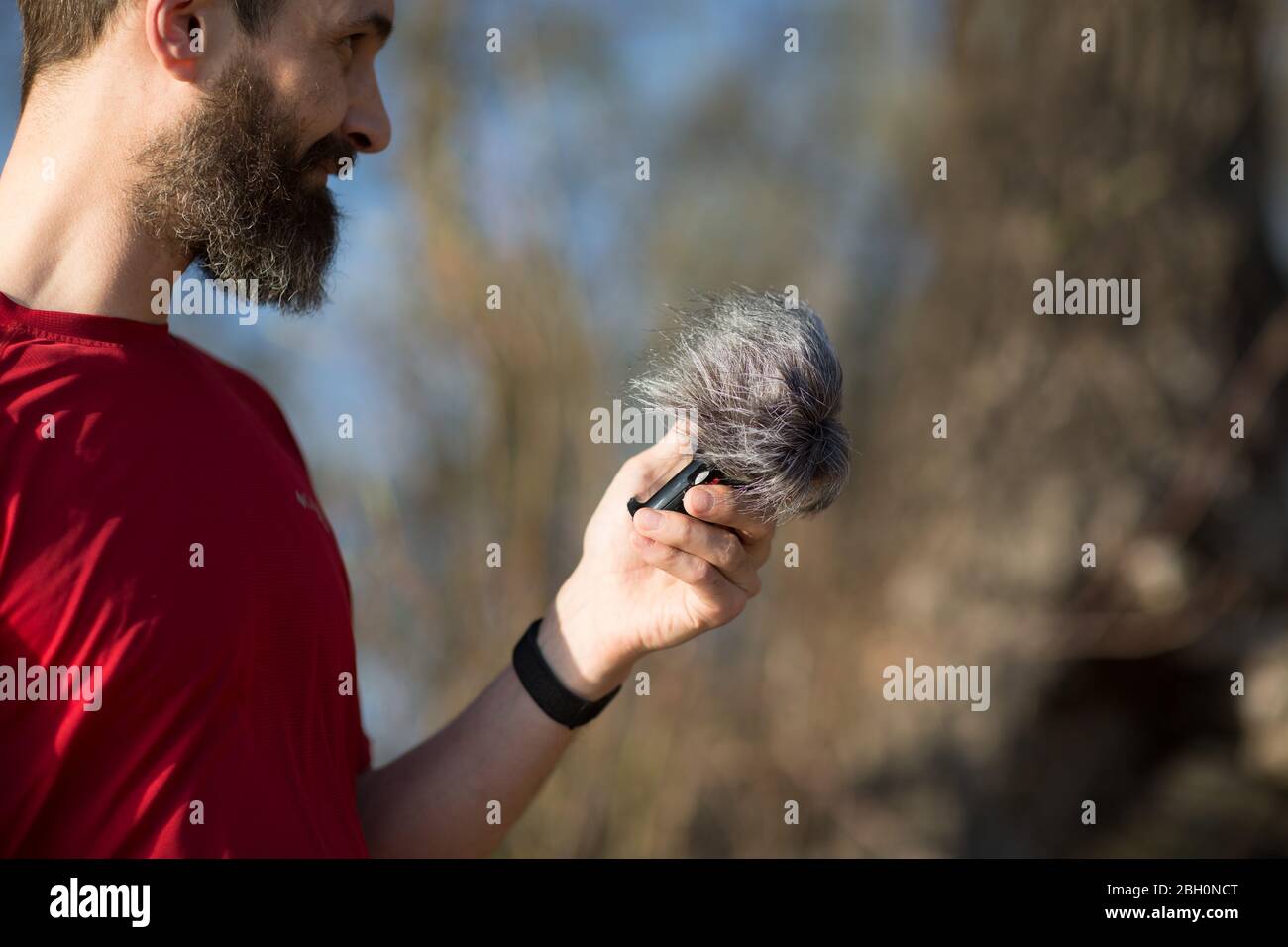 Bearded man holding microphone with a wind noise protection Stock Photo