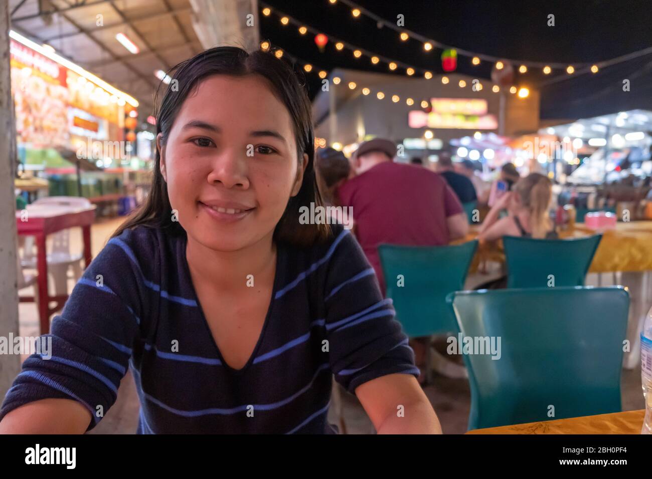 An asian women sitting at table and waiting her dinner at night bazaar. Stock Photo