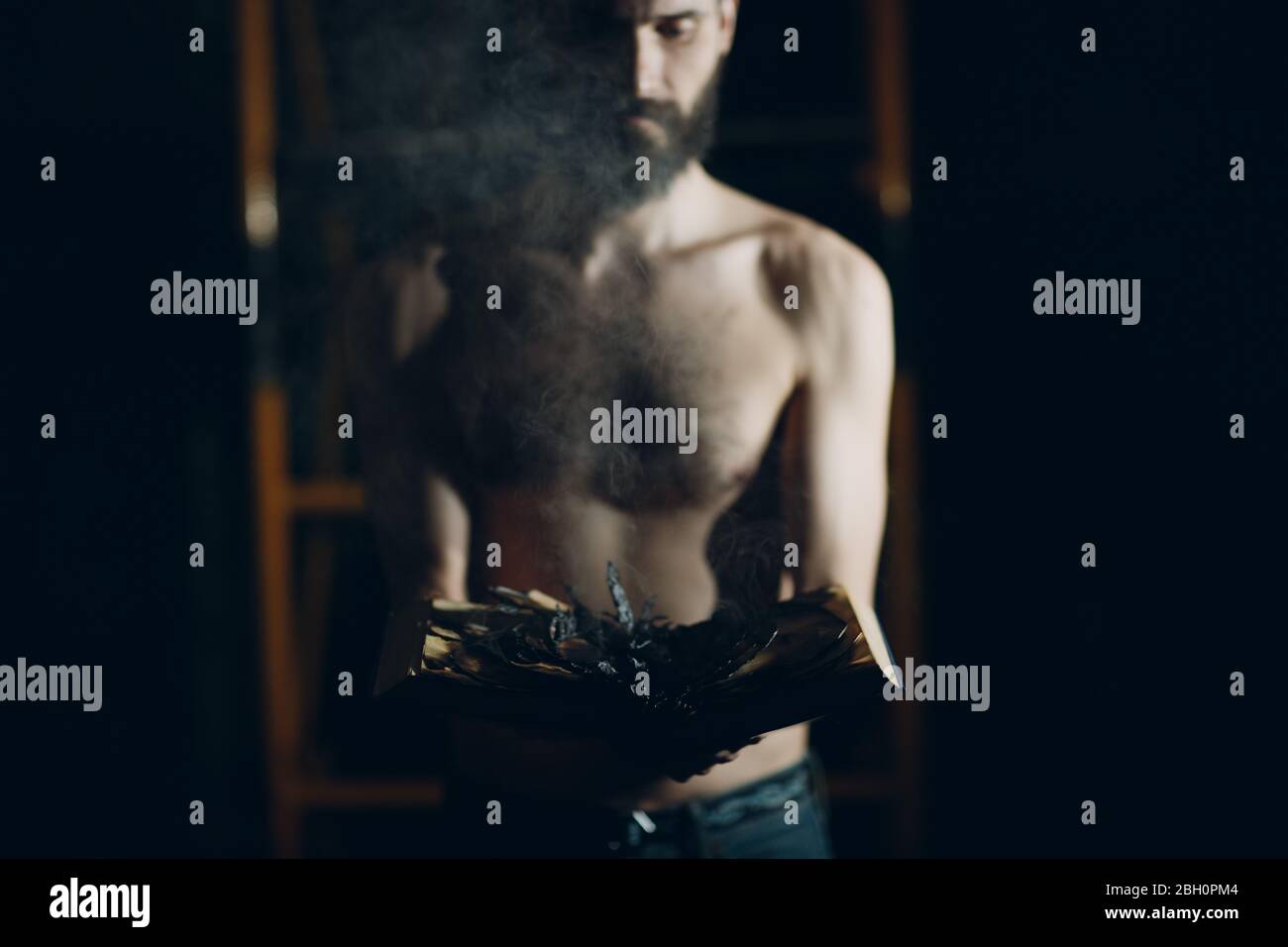 Man holds burning book in his hands. Stock Photo