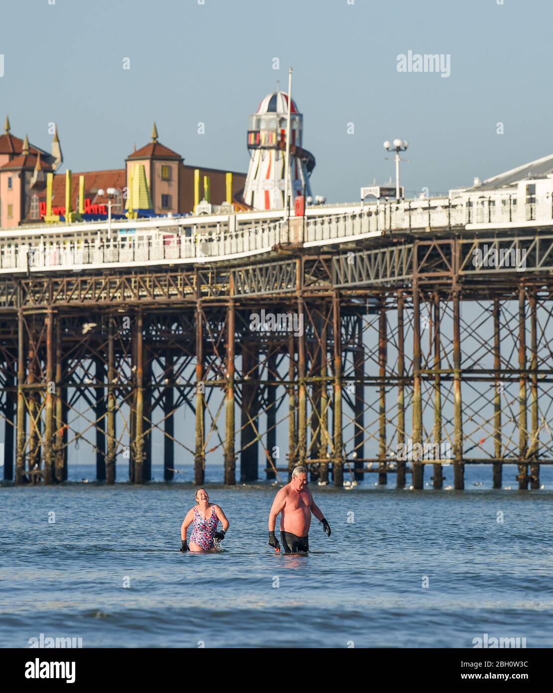 Brighton UK 23rd April 2020 - Early morning swimmers enjoy a dip in the sea by Brighton Palace Pier on a beautiful hot sunny day during the lockdown restrictions during the Coronavirus COVID-19 pandemic crisis  . Temperatures are expected to reach 25 degrees in some parts of the South East today .  Credit: Simon Dack / Alamy Live News Stock Photo