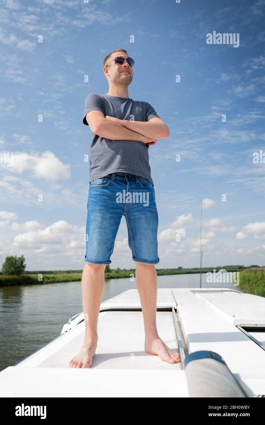 a man standing on flats boat platform uses pole to push through