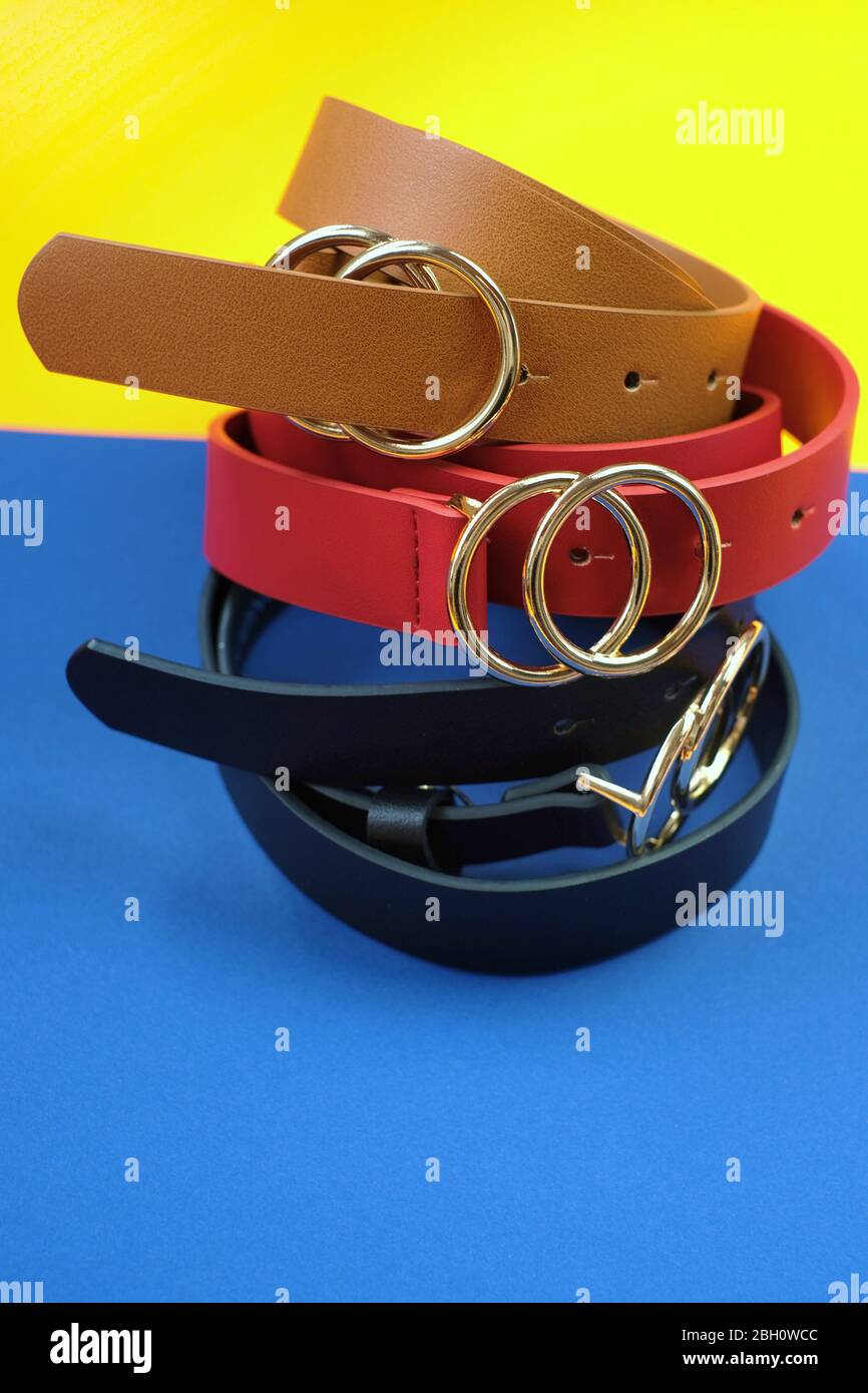 Belts collection.Leather belts set. Fashion accessory. Red, brown, black leather natural belt on a combined yellow blue background. Stock Photo