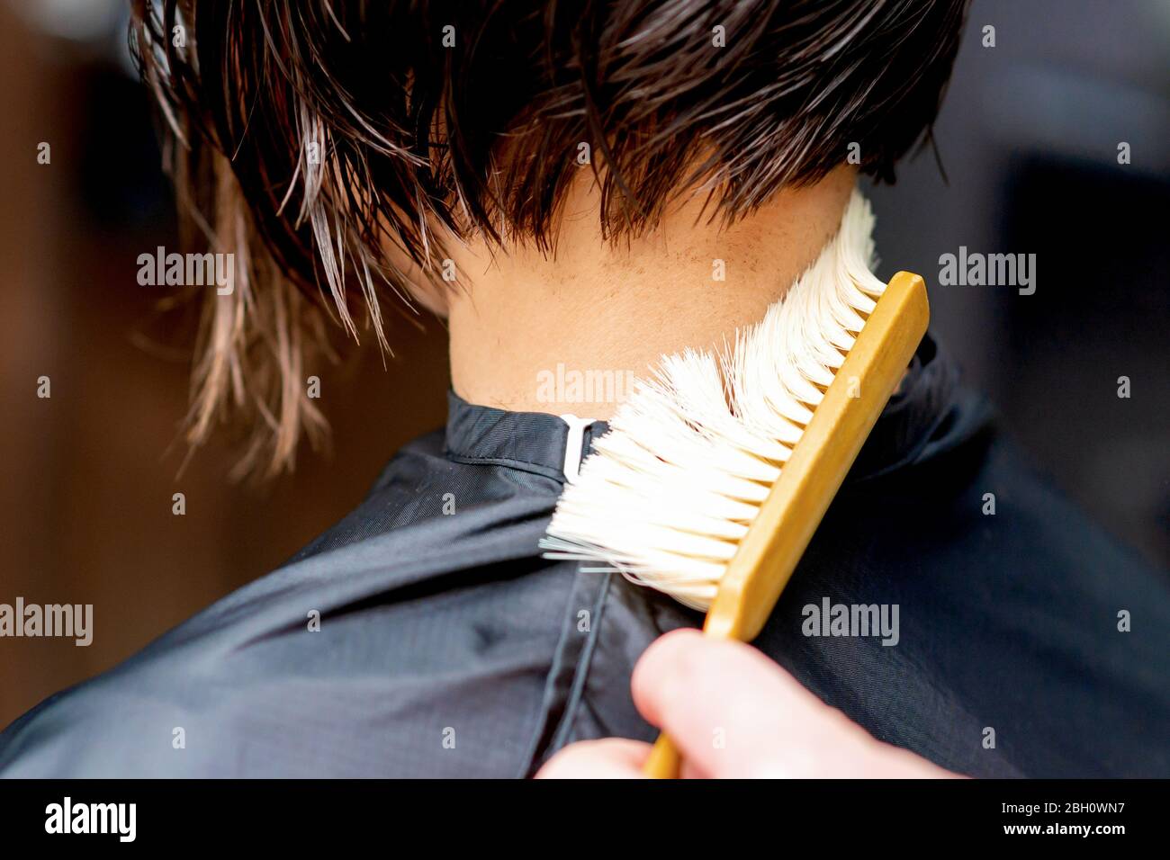 Hand os hairdresser is cleaning neck with brush from cutted hair after