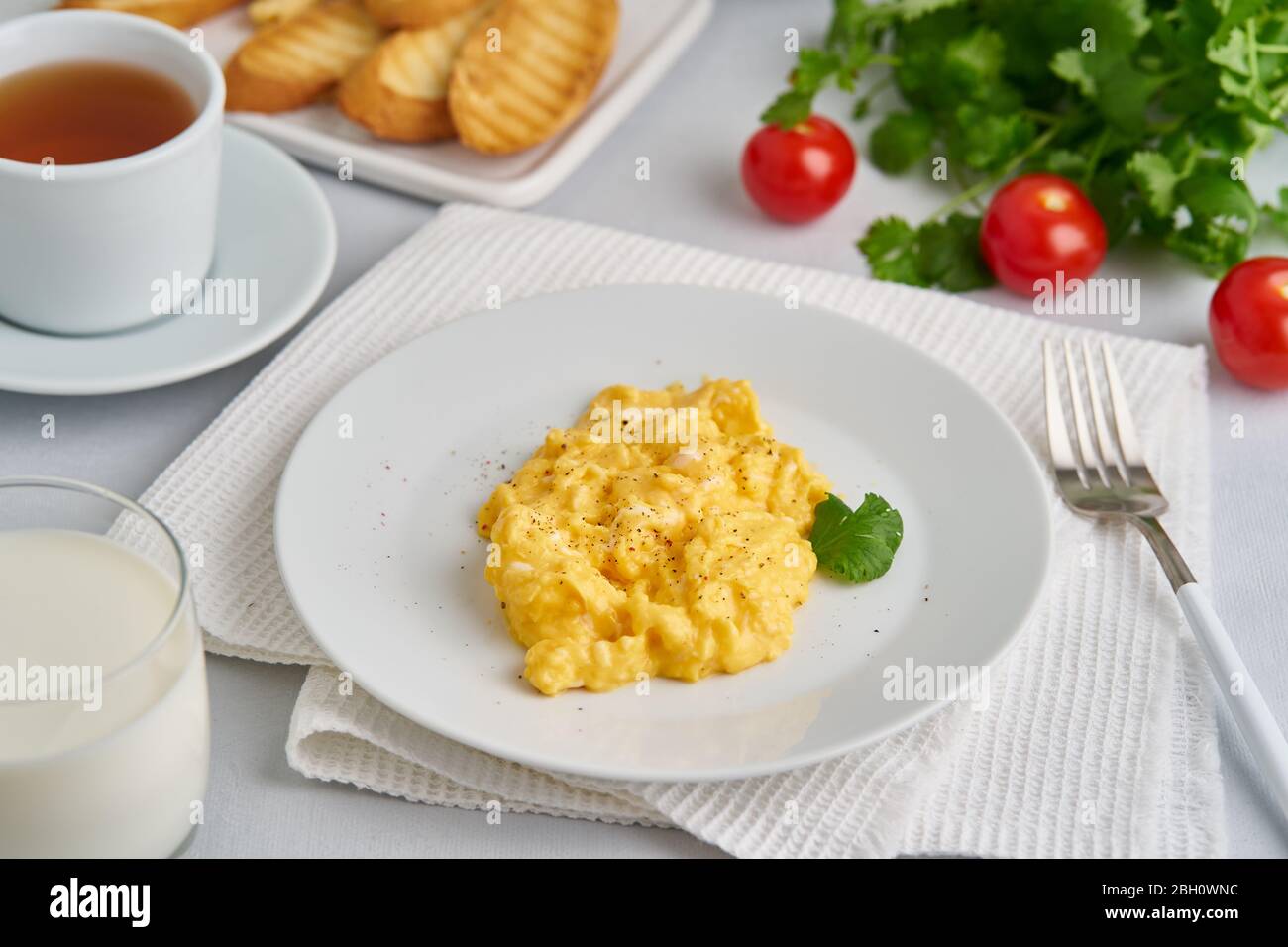 Scrambled eggs, omelet, side view. Breakfast with panfried eggs, glass