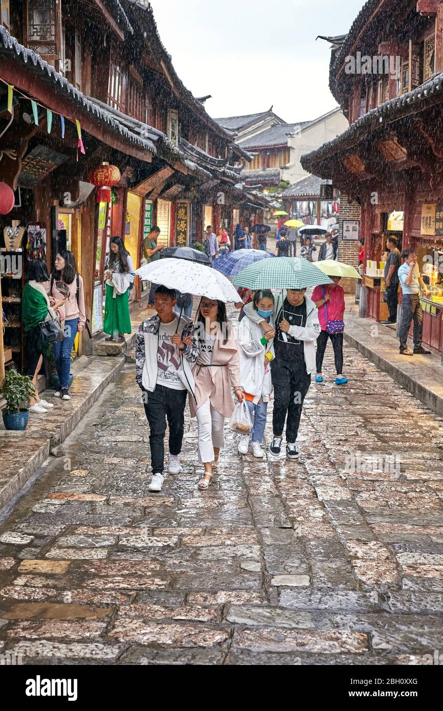 Lijiang, China - September 22, 2017: People on the street of Old Town on a rainy day. Old Town of Lijiang was included in the UNESCO World Cultural He Stock Photo
