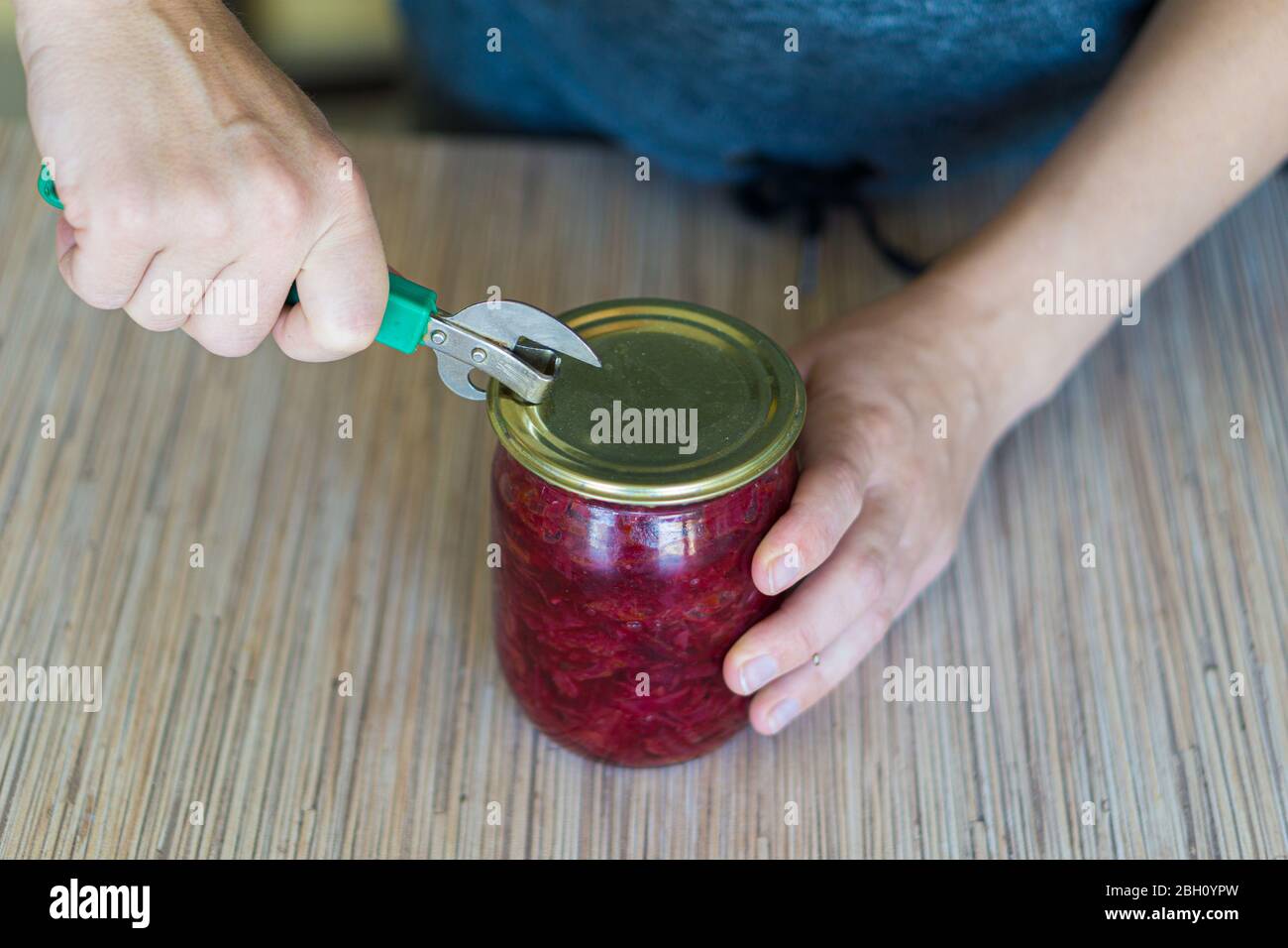 https://c8.alamy.com/comp/2BH0YPW/a-woman-in-the-kitchen-opens-a-can-of-canned-borscht-with-a-hand-held-can-opener-2BH0YPW.jpg