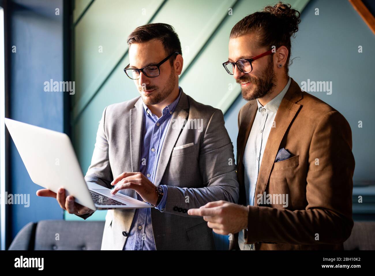 Sharing fresh ideas. Group of young business people in smart casual wear talking and smiling Stock Photo