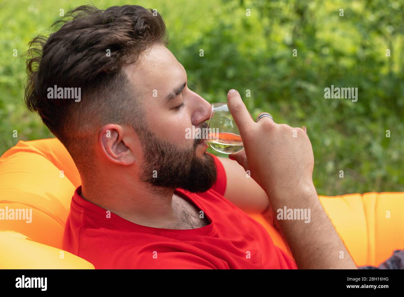 Portrait of handsome young man smelling wine in his glass and keeping ...