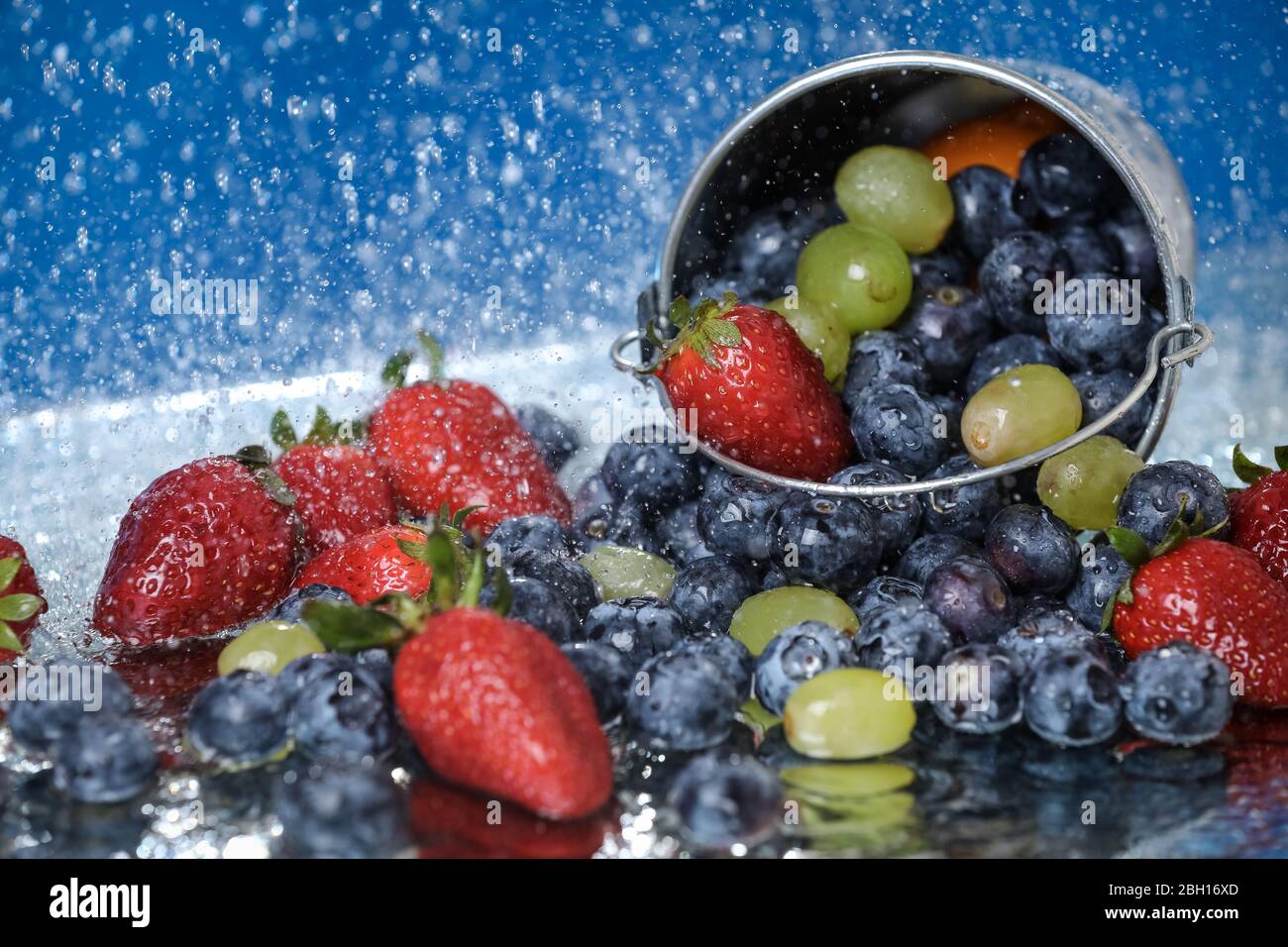 Fruit salad close up in falling metal bucket. Strawberry, grape ... Fruit salad close up in falling metal bucket. Strawberry, grape ...