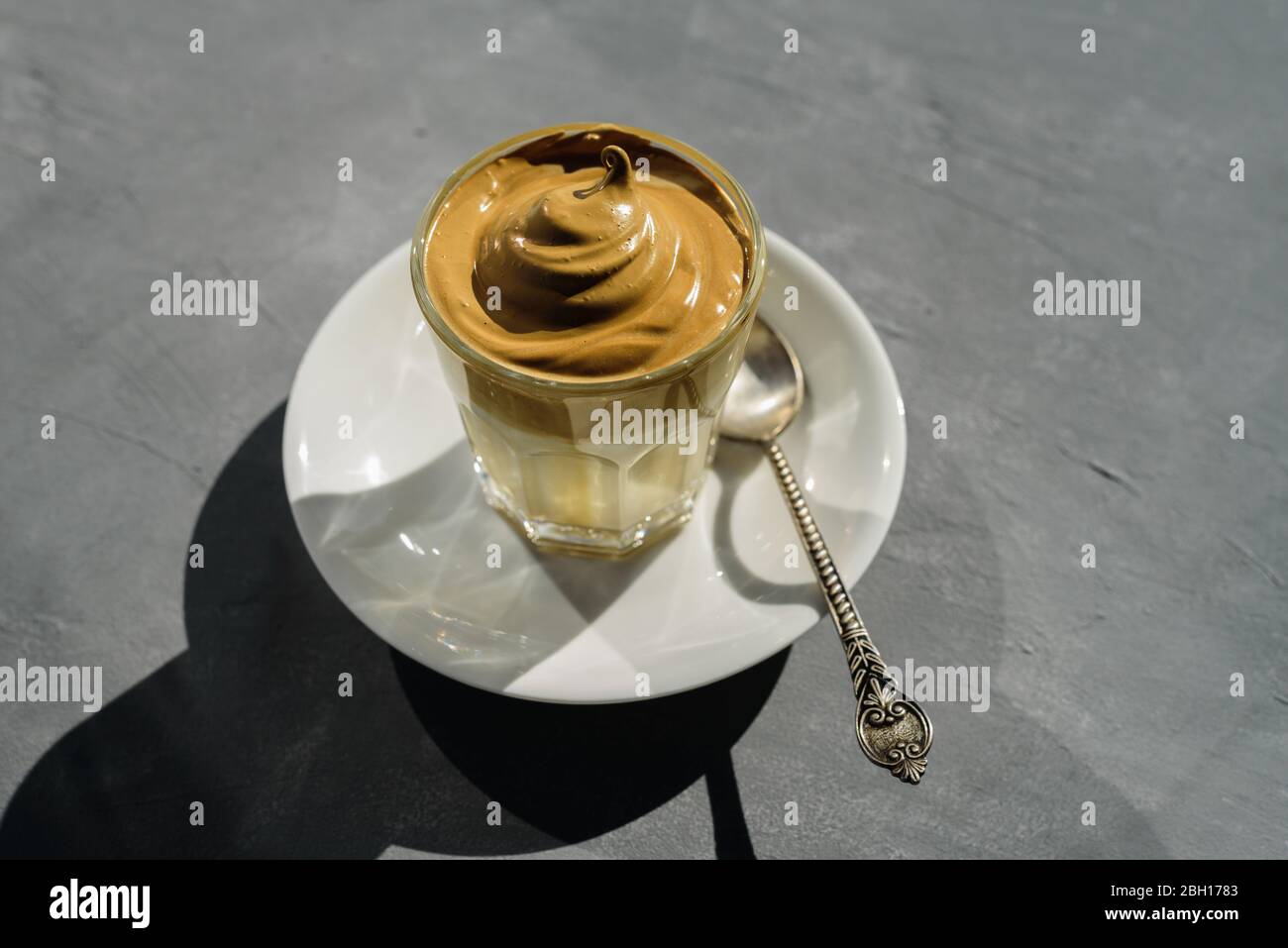 Dalgona instant coffee whipped drink in glass with plate and spoon