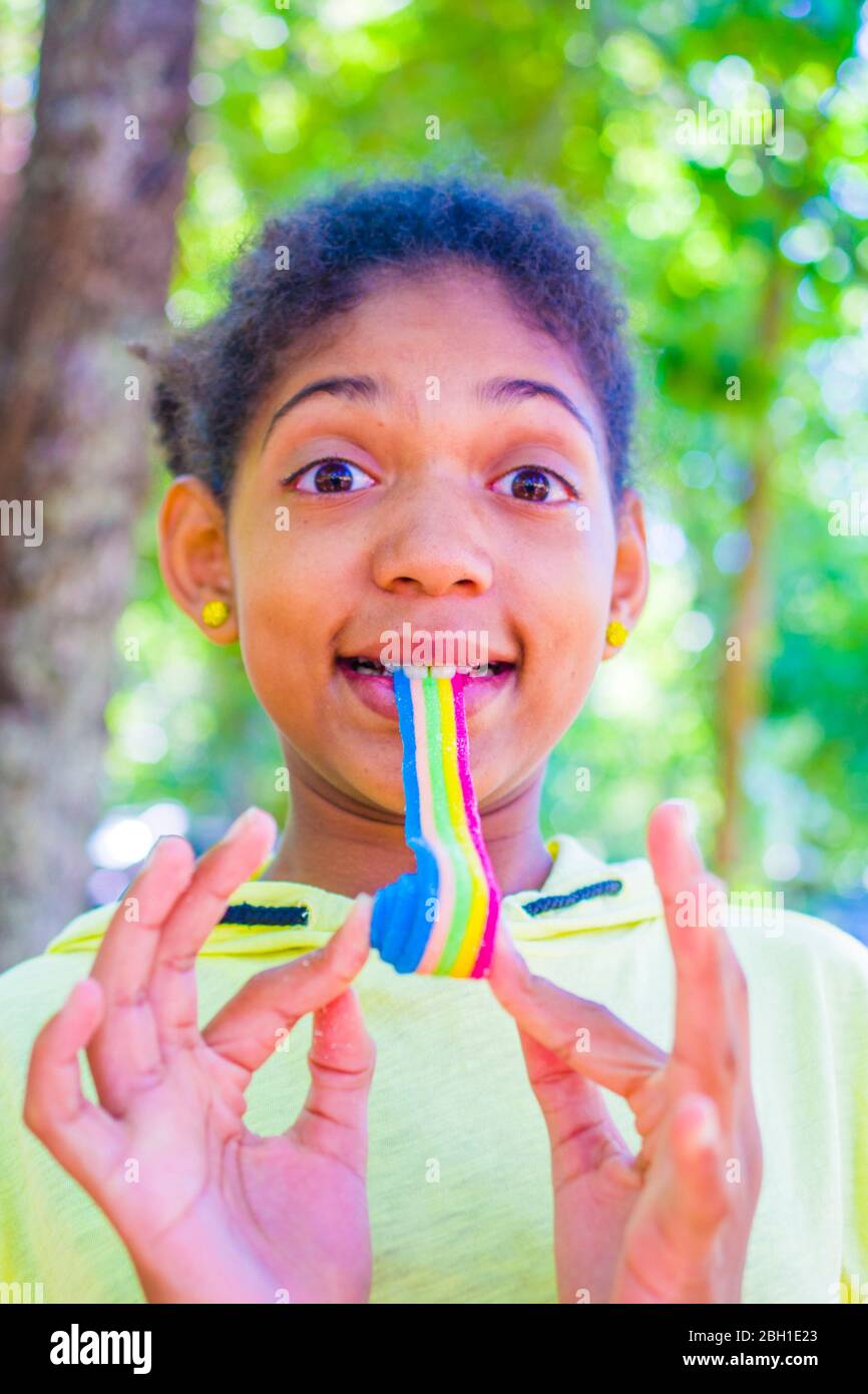 happy little girl smiles as she eats a soft licorice of all colors