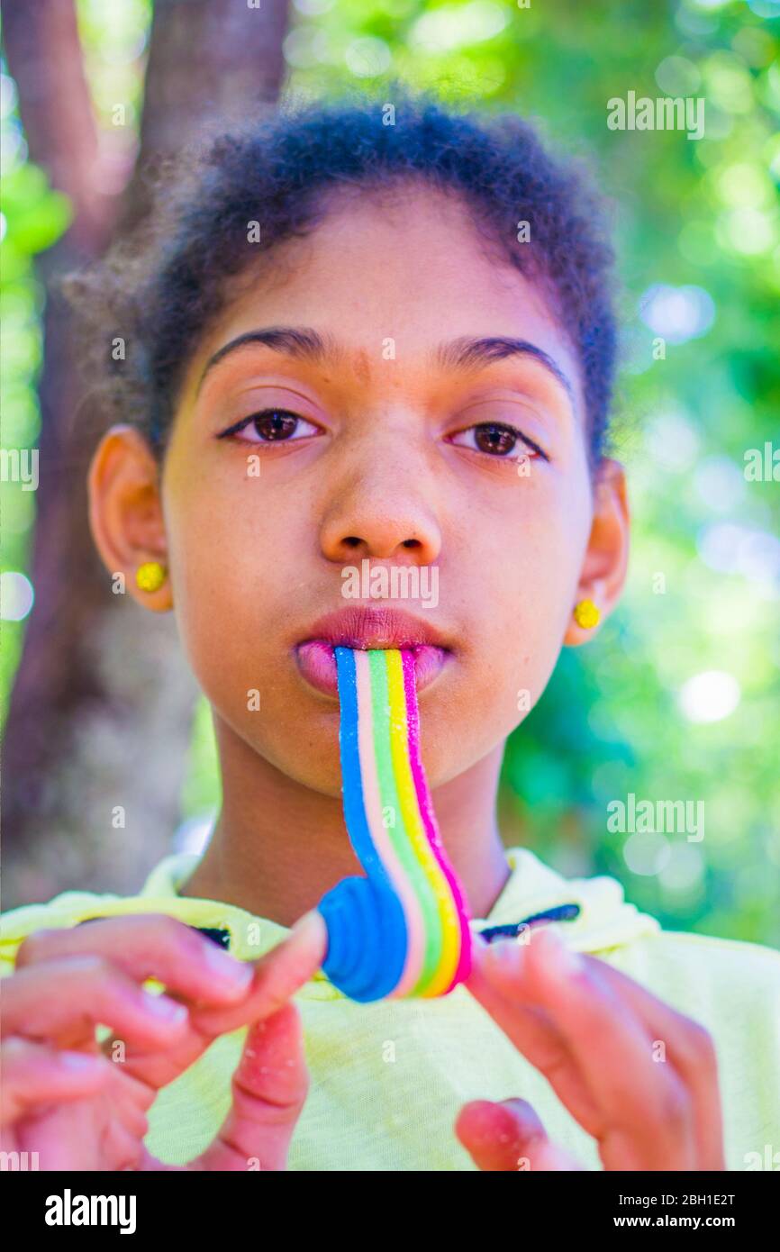 happy little girl smiles as she eats a soft licorice of all colors